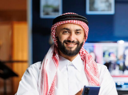 Smiling Muslim guy holding a cell phone